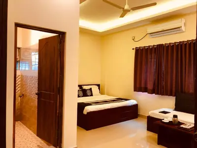 a bedroom with a bed and a bathroom with a shower at Palm Era Resorts in Kushālnagar
