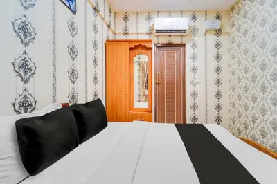 a bedroom with a white bed and a wooden door at Super Hotel O Airport Road Coimbatore in Coimbatore