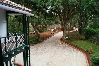 a walkway in a park with trees and a building at Fairy Glen in Coonoor