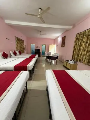 a row of beds in a room with a table at KSTDC Hotel Mayura Riverview Srirangapatna in Seringapatam