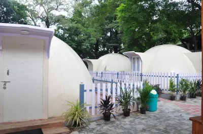two domes in a yard with a fence and plants at KSTDC Hotel Mayura Riverview Srirangapatna in Seringapatam