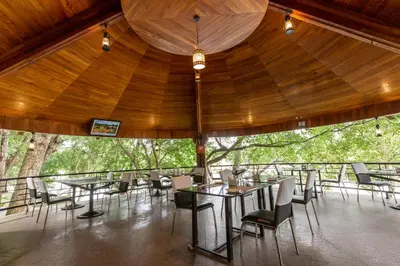 a large room with tables and chairs and trees at KSTDC Hotel Mayura Riverview Srirangapatna in Seringapatam