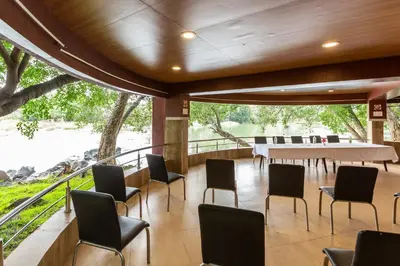 a dining room with a table and chairs and a large window at KSTDC Hotel Mayura Riverview Srirangapatna in Seringapatam