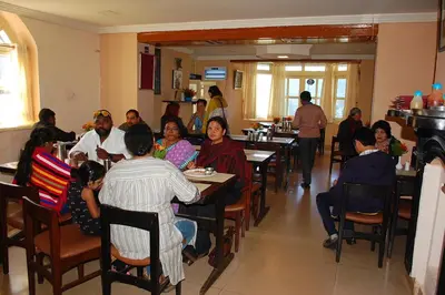 a group of people sitting at tables in a restaurant at KSTDC Hotel Mayura Sudarshan ,Ooty in Ooty