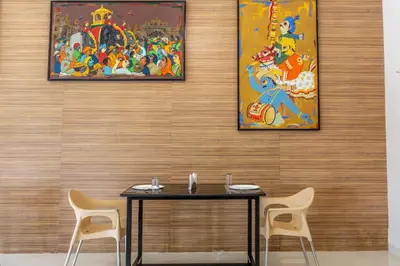 a table with two chairs and a painting on a wall at KSTDC Hotel Mayura Kauvery KRS in Hosa Kannambādi