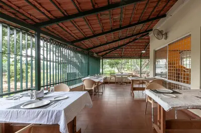 a restaurant with tables and chairs and large windows at KSTDC Hotel Mayura Sangama Mekedatu in Mulhalli
