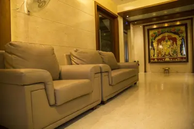a living room with two couches and a painting at Hotel Sri Sakthi in Tiruppūr