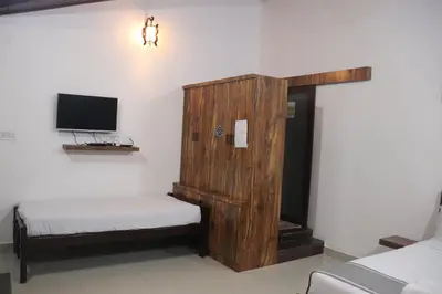 a room with a wooden cabinet and a tv at Coorg North Breeze Homestay in Madikeri