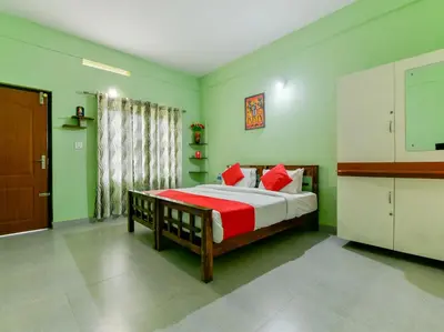 a bedroom with a bed with red pillows and green walls at Gooseberry Family Retreats - Wayanad by KARAPUZHA RESORTS in Meenangadi