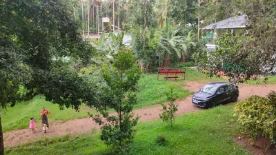 a man and two children walking in a yard with a car at Gooseberry Family Retreats - Wayanad by KARAPUZHA RESORTS in Meenangadi