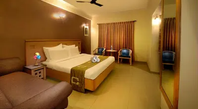 a bedroom with a bed and a chair and a couch at Plaza Inn in Coimbatore