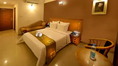 a hotel room with a large bed and a table at Plaza Inn in Coimbatore