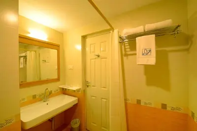 a bathroom with a sink and a shower with a mirror at Plaza Inn in Coimbatore