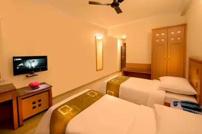 a hotel room with two beds and a flat screen tv at Plaza Inn in Coimbatore