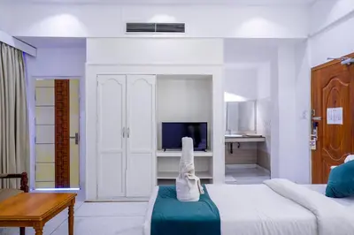 a white room with a bed and a television at Casino Hotels Ltd in Trichūr