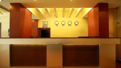 a lobby with two clocks on the wall and a counter at Hotel Palace Tower in Trichūr