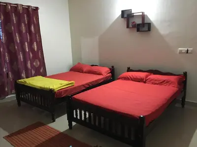 two beds in a room with red and yellow sheets at Vacanza Estate House in Kakkabe
