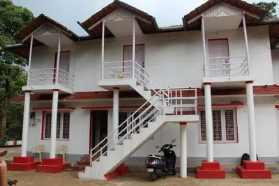 a white house with a motorcycle parked in front of it at Vacanza Estate House in Kakkabe