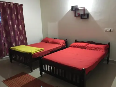 two beds in a room with red and yellow sheets at Vacanza Estate House in Kakkabe