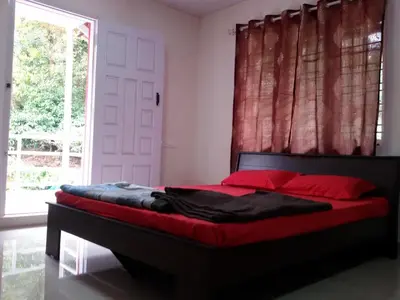 a bedroom with a bed with red pillows and a window at Vacanza Estate House in Kakkabe