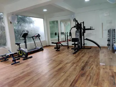 a gym with several treadmills and exercise bikes at Woodrose Resort in Kalpetta