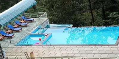 a large swimming pool with chairs and a swimming pool at Woodrose Resort in Kalpetta