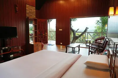 a bedroom with a bed and a view of a balcony at Woodrose Resort in Kalpetta