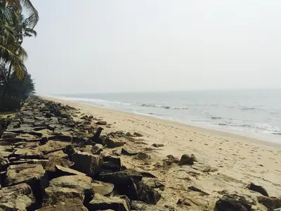 a sandy beach with rocks and the ocean at Majo House in Cherai Beach