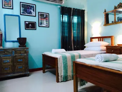 a bedroom with two beds and a dresser and a mirror at Majo House in Cherai Beach