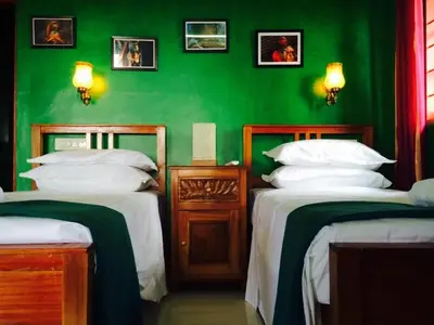 a green room with two beds and a green wall at Majo House in Cherai Beach