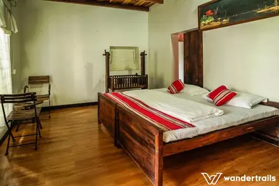 a bedroom with a large wooden bed with red pillows at Teak Town in Nilambūr