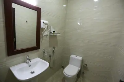 a bathroom with a sink and a toilet and a mirror at Hotel White City in North Paravur