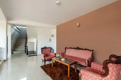 a living room with two chairs and a table at Treebo Vrindavan, 3 Km From Madikeri Fort in Madikeri