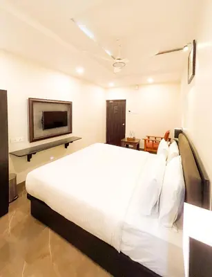 a bedroom with a white bed and a flat screen tv at Shree Residency in Erode