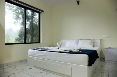 a bedroom with a large white bed with a window at Green Garden Jasmin Cottage in Vayittiri