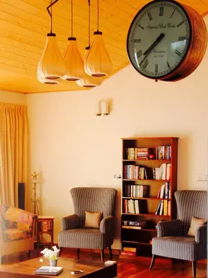 a living room with two chairs and a clock on the wall at The Xanadu, Coonoor in Coonoor