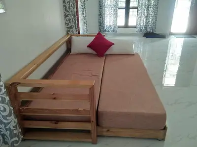 a wooden bed in a room with a red pillow at Coconut Garden in Cherai Beach