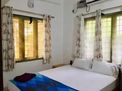 a bedroom with a bed and two windows at Coconut Garden in Cherai Beach
