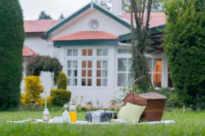 a picnic in the grass in front of a house at SaffronStays Milton Abbott Estate - 2BR colonial-era bungalow with garden, golf course views & bonfire nights near Ooty Golf Club in Ooty