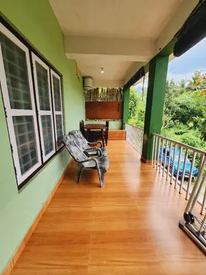 a porch of a house with a bench on a wooden floor at Wildways Mudumalai Homestay in Masinagudi