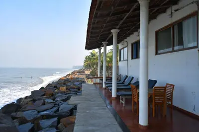 a building with chairs and tables next to the ocean at Cherai Onetree Retreat in Cherai Beach