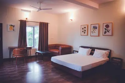 a bedroom with a bed and a chair and a window at Forestdale Coorg in Virajpet