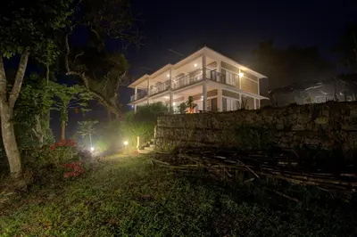 a large white house at night with lights at Forestdale Coorg in Virajpet