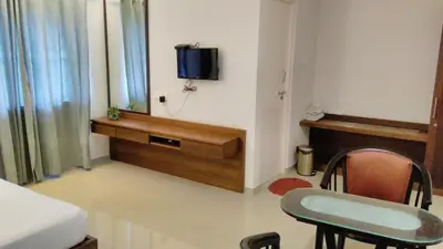 a room with a bed and a tv on a wall at Nalanda Inn in Palakkad