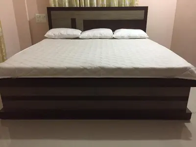 a bed with a wooden frame and white mattress at Mega Tourist Home in Guruvāyūr