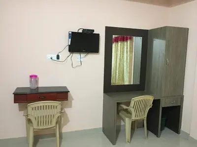 a room with a desk and a mirror and two chairs at Mega Tourist Home in Guruvāyūr