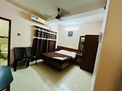a bedroom with a bed and a table and chairs at Hotel Jothi in Coimbatore