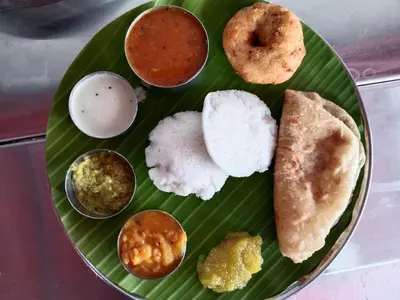 a green plate with different types of food on it at Hotel Jothi in Coimbatore