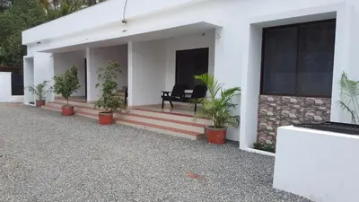 a white house with potted plants on the porch at The Rubis in Kottakkal