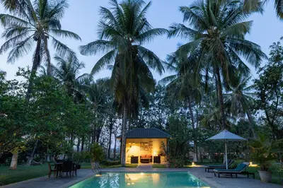 a villa with a swimming pool and palm trees at The Mangifera in Bandipūr